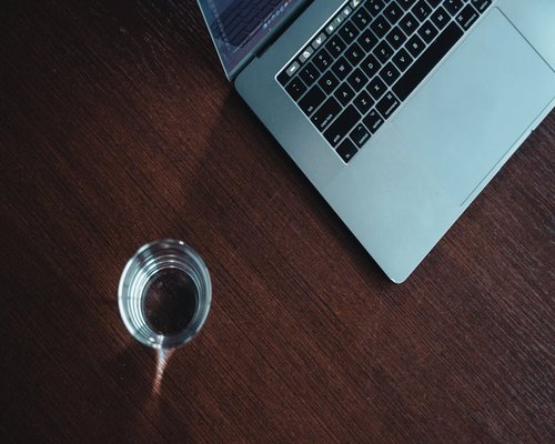 glass of water and a laptop on a modern office desk